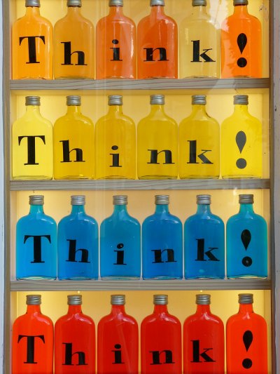 Rows of bottles filled with coloured water labelled "think".